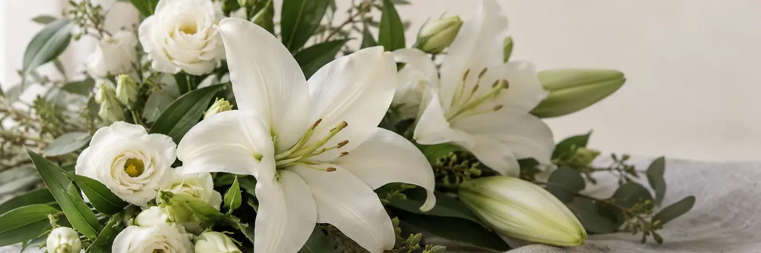 Weiße Lilien und cremefarbene Lisianthus auf hellgrauem Leinen.